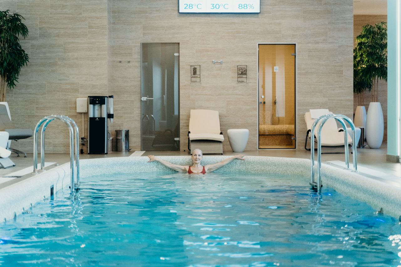 Senior woman enjoying a serene swim in an indoor spa pool with modern amenities.