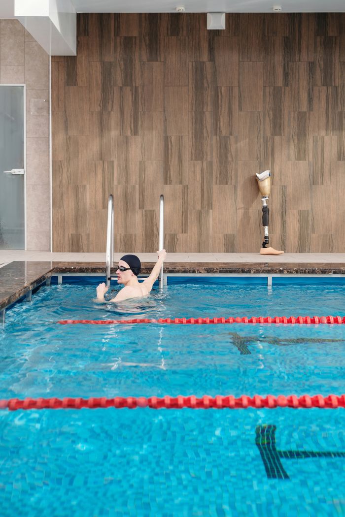 Swimmer with prosthetic leg practices in an indoor pool for adaptive swimming training.